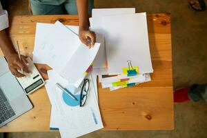 secretary searches through stacked documents on desk in office to find lease within stacked documents just before meeting. concept difficulty in finding hire purchase contract from stacked documents photo