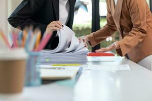 secretary searches through stacked documents on desk in office to find lease within stacked documents just before meeting. concept difficulty in finding hire purchase contract from stacked documents photo