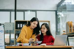 Two Attractive young Asian female college students working on the school project using laptop computer and tablet together, enjoy talking photo