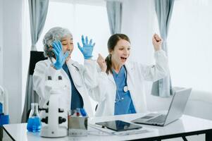 Medical team having a meeting with doctors in white lab coats and surgical scrubs seated at a table discussing a patients working online using computers in the medical industry photo