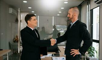 dos hombres de negocios confiados estrechando la mano durante una reunión en la oficina, éxito, trato, saludo y socio foto