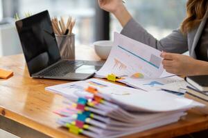 secretary searches through stacked documents on desk in office to find lease within stacked documents just before meeting. concept difficulty in finding hire purchase contract from stacked documents photo