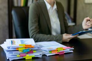 secretary searches through stacked documents on desk in office to find lease within stacked documents just before meeting. concept difficulty in finding hire purchase contract from stacked documents photo