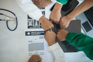 The medical team joins hands after the meeting and discusses the treatment of severely ill patients and can come to a conclusion on the surgical treatment of the patient. Medical team meeting concept photo