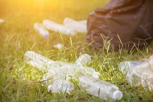 men collect plastic bottles on lawns and walkways in park and put them in bags to help keep them clean They can also collect plastic bottles for recycling. reducing environmental problems by recycling photo