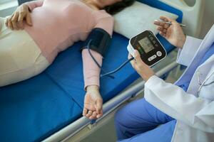 The doctor is using a blood pressure monitor on an elderly patient to check whether the blood pressure is abnormally high or not because hypertension often happens to the elderly and is dangerous. photo