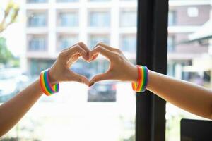 el lgbt q Pareja vistió lgbt q arco iris pulseras y usado su manos a formar un corazón símbolo a simbolizar amistad, amor y amabilidad y el lgbt q Pareja además prometido a amor cada otro para siempre. foto