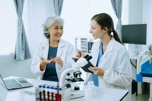 Two scientist or medical technician working, having a medical discuss meeting with an Asian senior female scientist supervisor in the laboratory with online reading, test samples and innovation photo