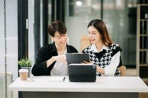 Two Asian business workers talking on the smartphone and using laptop at the modern office. photo