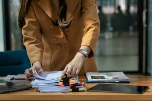 secretary searches through stacked documents on desk in office to find lease within stacked documents just before meeting. concept difficulty in finding hire purchase contract from stacked documents photo