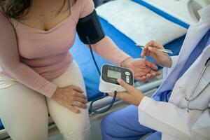 The doctor is using a blood pressure monitor on an elderly patient to check whether the blood pressure is abnormally high or not because hypertension often happens to the elderly and is dangerous. photo