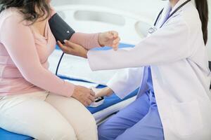 The doctor is using a blood pressure monitor on an elderly patient to check whether the blood pressure is abnormally high or not because hypertension often happens to the elderly and is dangerous. photo