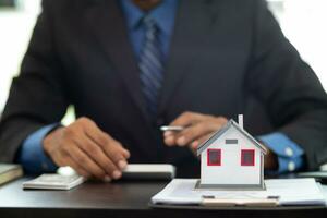 The real estate agent is reviewing the documents and calculating the interest rate to inform the tenant of the monthly installments to be paid before the real estate purchase agreement is finalized. photo