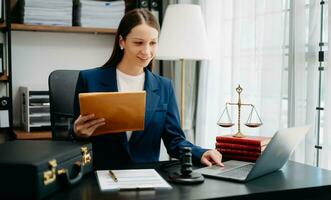 justice and law concept. Female judge in a courtroom  the gavel, working with smart phone and laptop and digital tablet computer on black  table photo