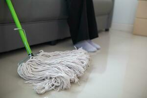 Cleaning staff is wiping cloth with cleaner and disinfectant on the surface of floor to make the floor clean with cleaning products and free from germs clinging to surface of the floor in living room. photo