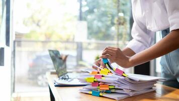 secretary searches through stacked documents on desk in office to find lease within stacked documents just before meeting. concept difficulty in finding hire purchase contract from stacked documents photo