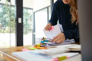 secretary searches through stacked documents on desk in office to find lease within stacked documents just before meeting. concept difficulty in finding hire purchase contract from stacked documents photo