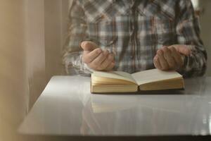 joven hombre estaba Orando a Dios en frente de Biblia con fe y poder de fe en dios. Biblia estudiar concepto a entender y orar a Dios con fe en enseñanzas de el Biblia estudió. Copiar espacio foto