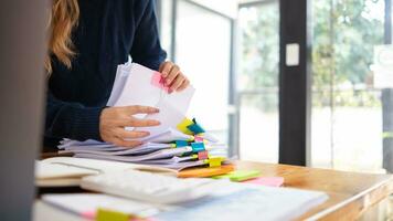 secretary searches through stacked paperwork on desk in office to find lease within stacked paperwork just before meeting. concept difficulty in finding hire purchase contract from stacked paperwork photo