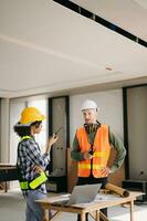 Architect caucasian man and woman working with colleagues mixed race in the construction site. Architecture engineering on big project. Building in construction process interior. photo