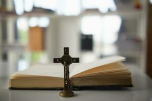 Cross represents God placed on Bible which is teaching of God according to Christian faith. cross and Bible were placed on table in room as they were prepared for prayers to God by faith. photo