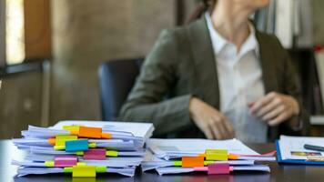 secretary searches through stacked documents on desk in office to find lease within stacked documents just before meeting. concept difficulty in finding hire purchase contract from stacked documents photo
