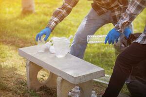 men collect plastic bottles on lawns and walkways in park and put them in bags to help keep them clean They can also collect plastic bottles for recycling. reducing environmental problems by recycling photo