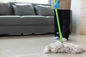 Cleaning staff is wiping cloth with cleaner and disinfectant on the surface of floor to make the floor clean with cleaning products and free from germs clinging to surface of the floor in living room. photo