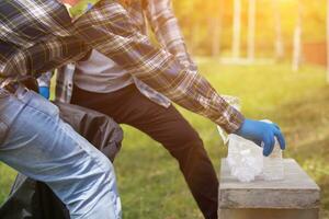 men collect plastic bottles on lawns and walkways in park and put them in bags to help keep them clean They can also collect plastic bottles for recycling. reducing environmental problems by recycling photo