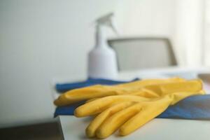 azul toalla y amarillo guantes fueron metido en de madera mesa para limpieza personal a utilizar a limpiar y evitar limpiador desde dermatitis. concepto de elegir limpieza empresa a limpiar el oficina foto