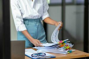 secretary searches through stacked documents on desk in office to find lease within stacked documents just before meeting. concept difficulty in finding hire purchase contract from stacked documents photo