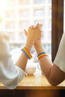 lgbt Q couple wore rainbow wristbands symbolizing lgbt Q group and held hands to show love, friendship and kindness. And lgbt Q couple also promised to love each other forever. Copy space for text photo