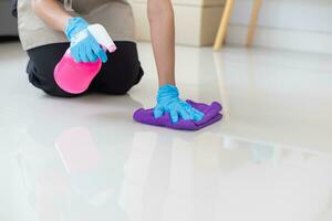 Cleaning staff is wiping cloth with cleaner and disinfectant on the surface of floor to make the floor clean with cleaning products and free from germs clinging to surface of the floor in living room. photo
