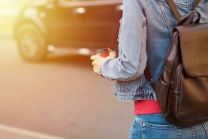 mano de mujer con una taza de café de papel para llevar en una calle de la ciudad foto