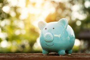 Blue piggy bank on wooden table over blurred green bokeh background. Saving money concept photo