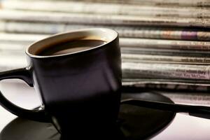 Cup of coffee and newspapers pile on the table. photo