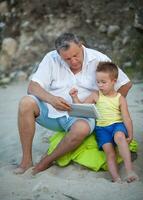 abuelo y nieto utilizando almohadilla en el playa foto