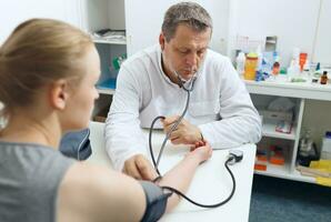 Doctor measures the blood pressure photo