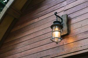 Aesthetic rustic wall lamp on facade of a house with wooden wall photo