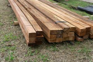 Wood timber construction material. Closeup big wooden boards. Stacked wooden beams of square section for house construction photo