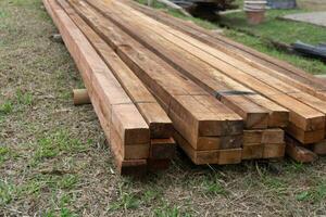 Wood timber construction material. Closeup big wooden boards. Stacked wooden beams of square section for house construction photo