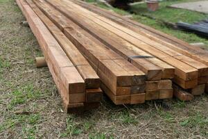 Wood timber construction material. Closeup big wooden boards. Stacked wooden beams of square section for house construction photo