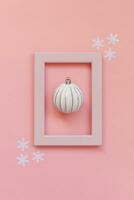 Simply minimal composition winter objects ornament ball in pink frame isolated on pink pastel trendy background photo