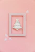 Simply minimal composition winter objects ornament fir tree in pink frame isolated on pink pastel trendy background photo