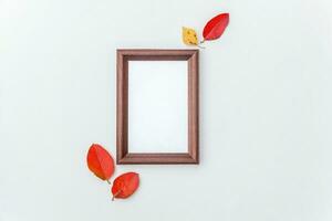 Autumn floral composition. Vertical photo frame mockup and colorful leaves on white background. Fall natural plants ecology fresh wallpaper concept. Flat lay top view, copy space