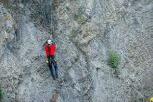 Climber placing safety nets to avoid falling rocks photo