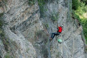 Climber placing safety nets to avoid falling rocks photo