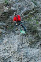 Climber placing safety nets to avoid falling rocks photo