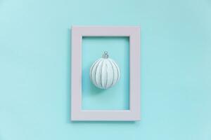 Simply minimal composition winter objects ornament ball in pink frame isolated on blue pastel trendy background photo