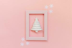 Simply minimal composition winter objects ornament fir tree in pink frame isolated on pink pastel trendy background photo